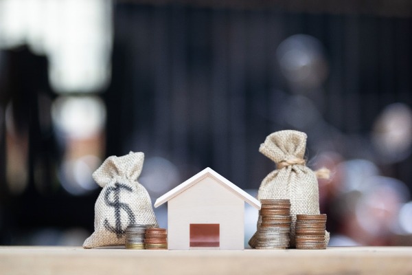 toy house, stacks of coins, and bags marked with a dollar sign