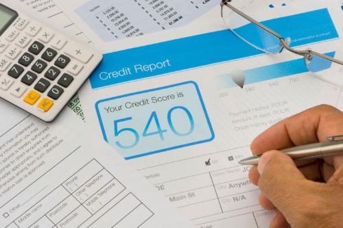 hand holding pen and filling out credit report info