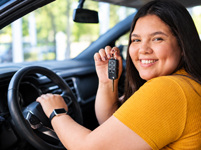 young woman holds key fob to new vehicle