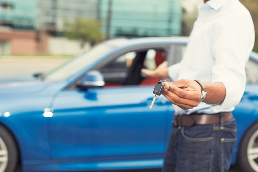 man holding car keys next to car