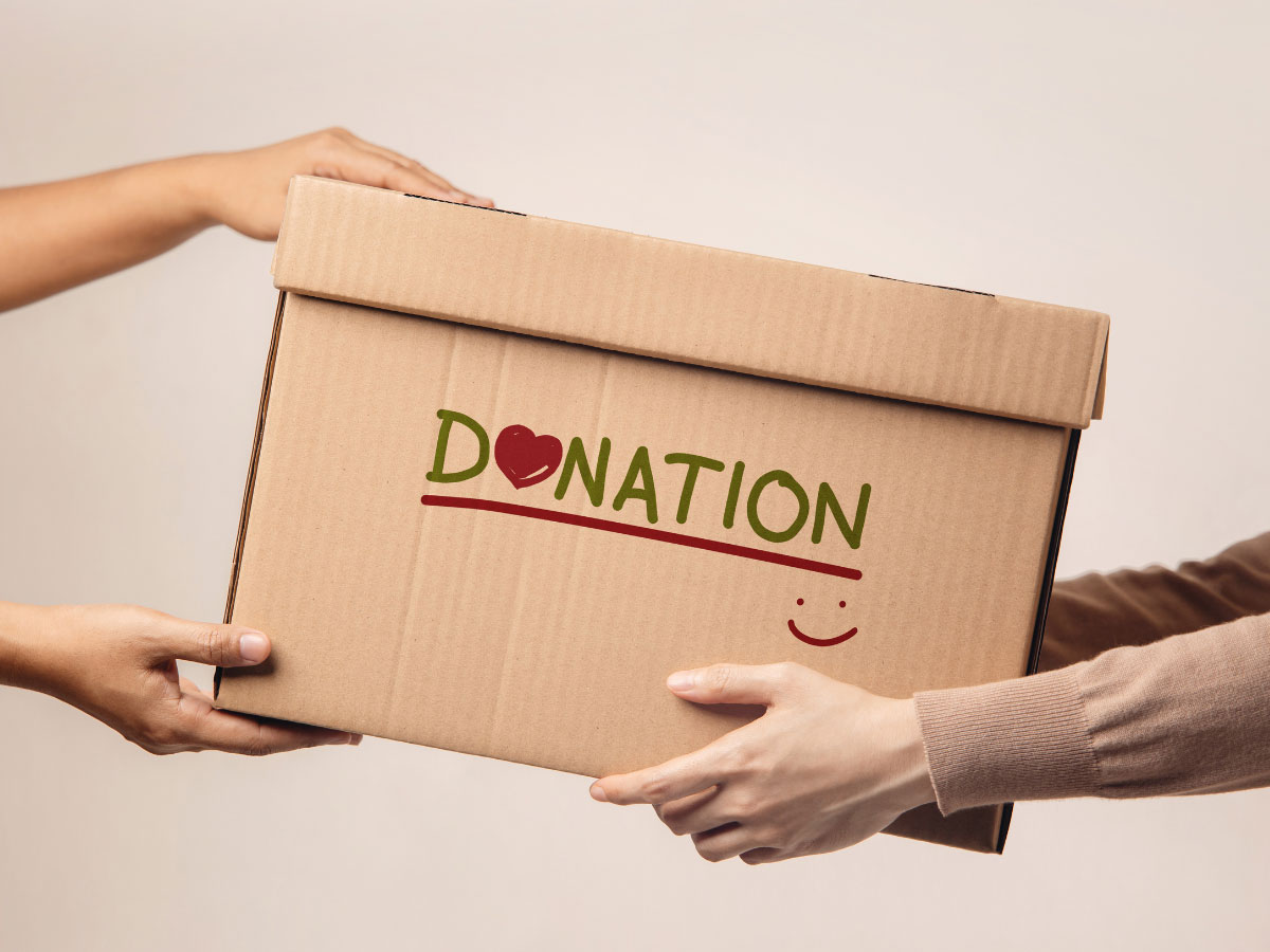 A donation box is being passed from one set of hands to another which starts the tax benefits of donating conversation