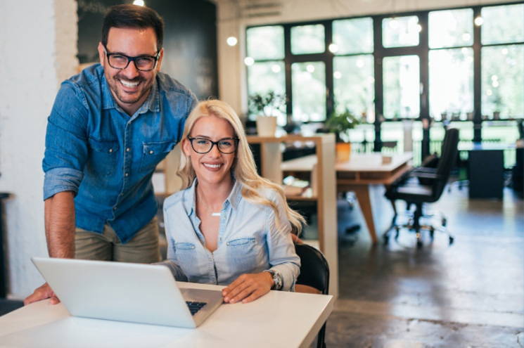 Business owner man and woman looking up from laptop