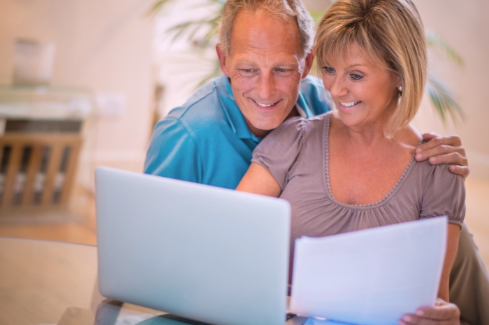 Middle-aged couple smile while looking at a laptop