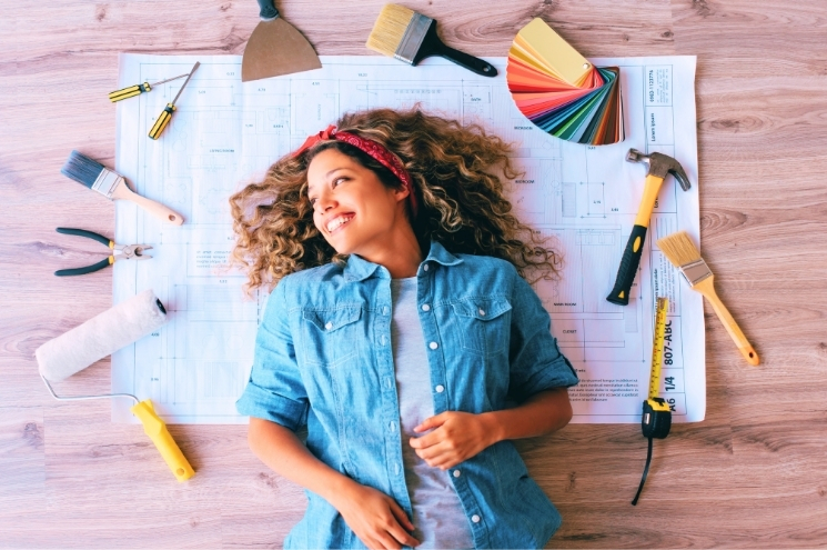 woman laying on floor surrounded by home improvement tools and plans