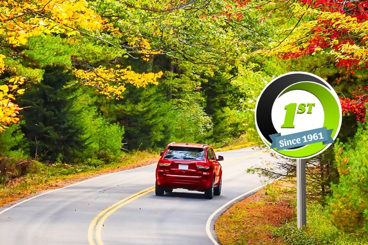 red vehicle drives on a road in Fall