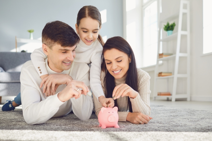 child with parents, putting money in piggy bank