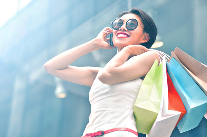 woman on the phone while carrying shopping bags