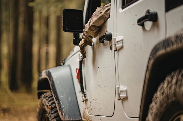 man hanging his arm out the window of a white Jeep