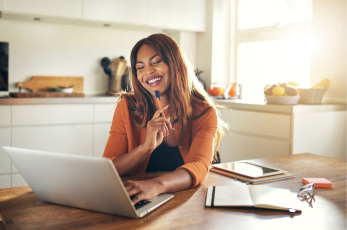 business woman in the corner of her kitchen working on a laptop