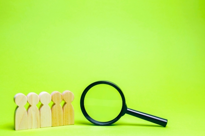 magnifying glass next to silhouettes of human shape