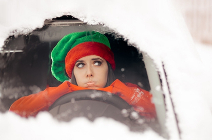 woman looking out from inside a snowed in vehicle