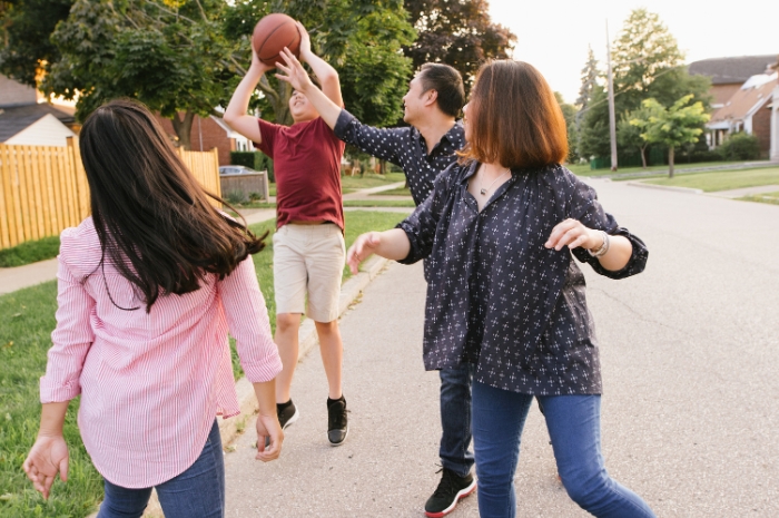 Mom and Dad playing hoops outside with teen daughter and son