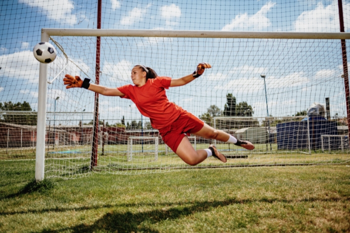 soccer goalie reaching for soccer ball